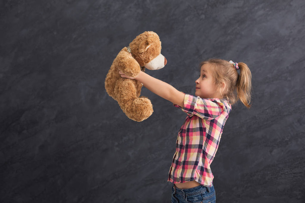 Happy little girl posing with teddy bear at grey background - Fotoğraf, Görsel