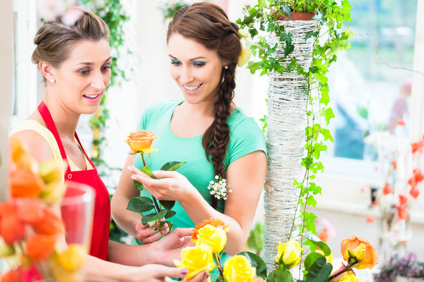 Kukkakauppias nainen myy ruusu kukkakimppu hänen naispuolinen asiakas
 - Valokuva, kuva