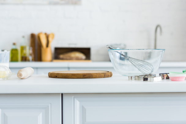 rolling pin, cutting board and bowl with whisk on kitchen counter - Φωτογραφία, εικόνα
