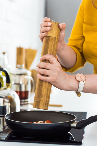 cropped image of woman adding spices to frying vegetables at kitchen - Photo, Image