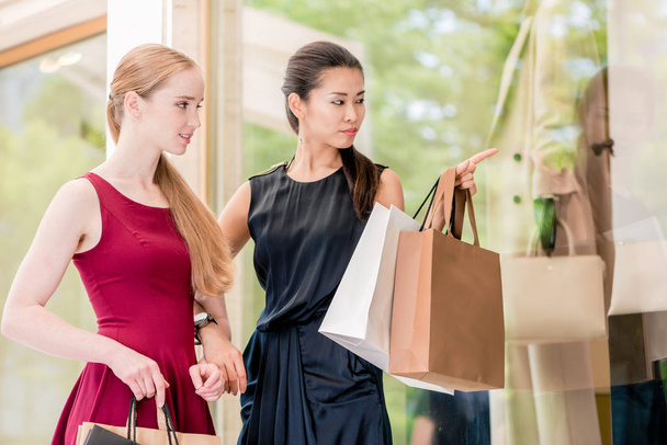 Дві жінки-найкращі друзі дивляться на останні модні тенденції з різними поглядами під час покупки в центрі міста
 - Фото, зображення