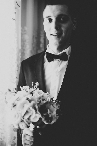 Happy handsome smiling groom posing with boutonniere - Foto, imagen