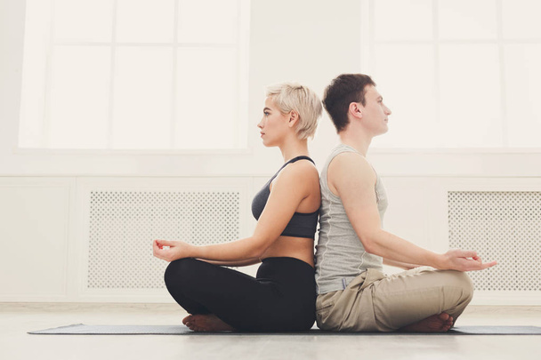 Casal jovem meditando juntos, de costas para trás
 - Foto, Imagem