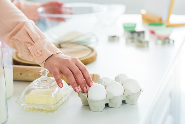 cropped image of woman taking eggs for dough at kitchen - 写真・画像