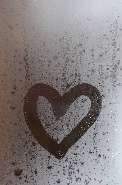 Corazón está pintado en el vidrio nebulizado en el invierno
 - Foto, Imagen
