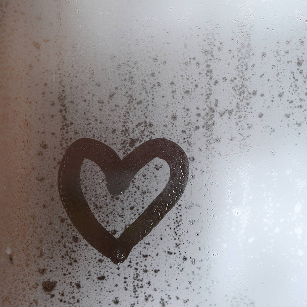 El corazón está pintado en el vidrio nebuloso en el invierno - Foto, imagen
