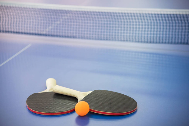 Bola naranja para tenis de mesa y dos raquetas de rojo y negro co
 - Foto, imagen