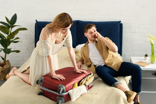 girlfriend and boyfriend packing travel bag for vacation in bedroom - Photo, Image