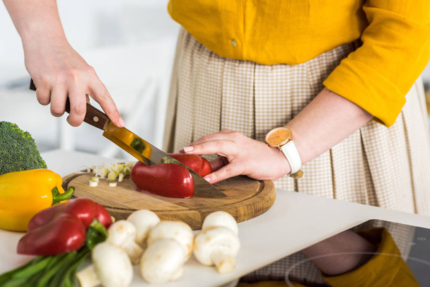 cropped image of woman cutting ripe bell pepper at kitchen - Фото, изображение
