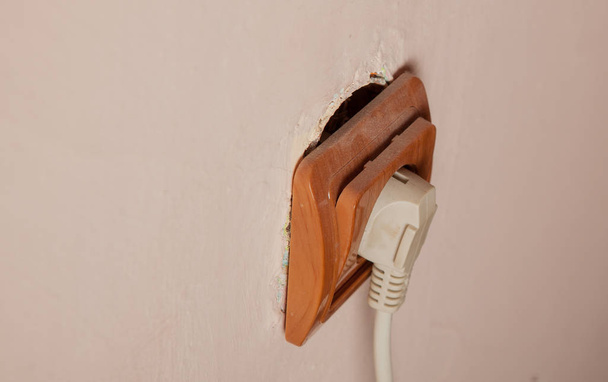 Old broken electrical socket fell out of wall. A violation of electrical safety - Fotó, kép