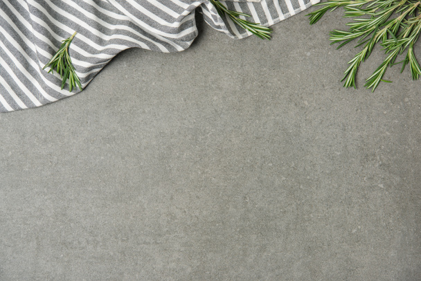 flat lay with rosemary twigs and striped linen on grey concrete surface - Fotoğraf, Görsel