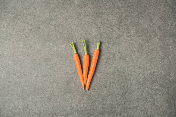 top view of arranged ripe carrots on grey concrete surface - Photo, Image