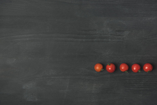 gearrangeerd cherry tomaten op donkere grijze oppervlak (bovenaanzicht) - Foto, afbeelding