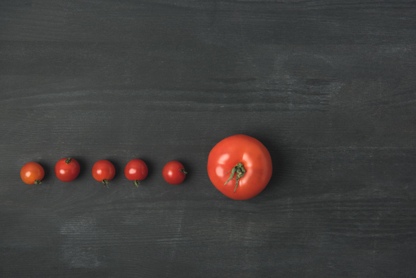 tendido plano con arreglo de tomate maduro y tomates cherry sobre la mesa gris oscuro
 - Foto, Imagen