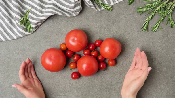 fermo immagine con mani femminili e pomodori freschi su tavolo in cemento grigio con rosmarino e lino
 - Filmati, video