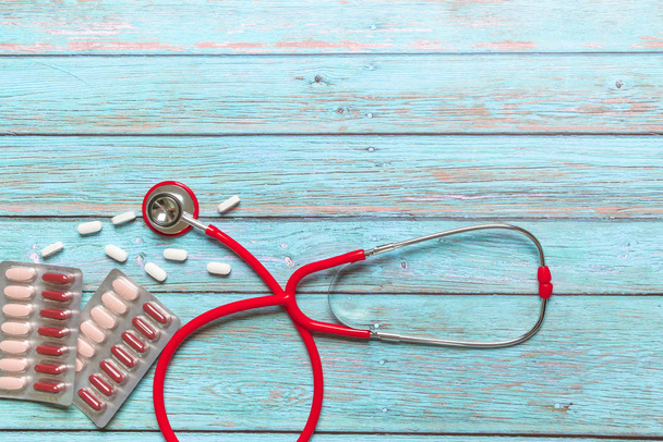 Świat zdrowia dzień opieki zdrowotnej i medycznej koncepcja czerwony stetoskop i lek na niebieskim tle drewnianych - Zdjęcie, obraz