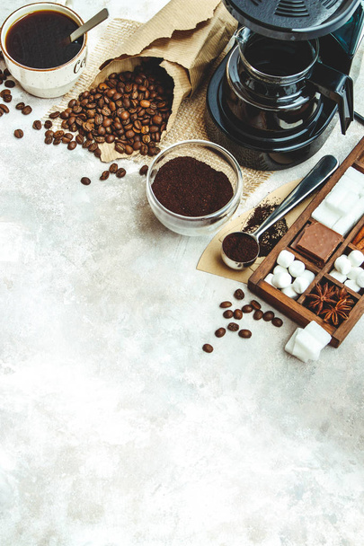 Variety things for prepare coffee. Roasted beans, ground coffee, scoop, electric coffee machine and assortment of sweets and spices to eat with on light background. Top view copyspace - Fotó, kép
