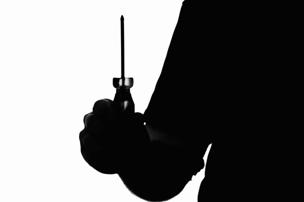 Silhouette of a man holding a screwdriver.  - Photo, image
