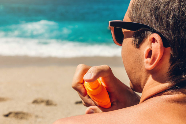 Krém napvédő. Az ember spray naptej a vállán. Skin care koncepciót. Egészséges bőr a nyaralás. - Fotó, kép