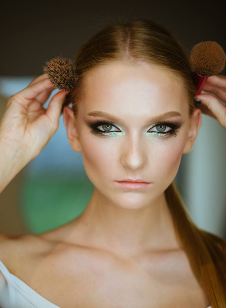 Woman with blond hair and makeup brushes, beauty. Woman with makeup face hold brushes at head. Girl with young skin face, skincare, youth. Beauty model with glamour look, hairstyle. - Foto, imagen