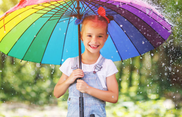 Feliz niña se ríe y juega bajo la lluvia de verano con un paraguas
 - Foto, Imagen