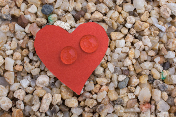 Gotas de agua sobre un papel en forma de corazón sobre fondo de arena
 - Foto, Imagen