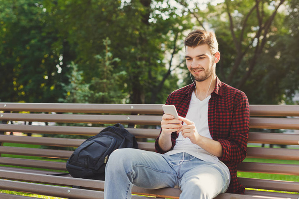 Happy young man using smartphone outdoors - Photo, Image