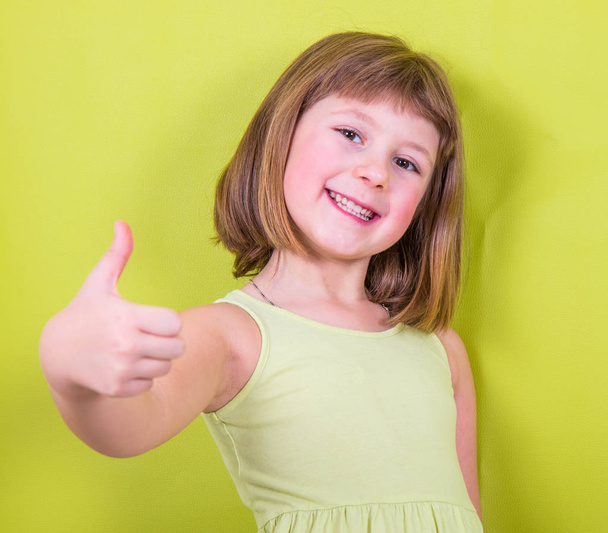     smiling little girl with thumbs up  - Foto, immagini