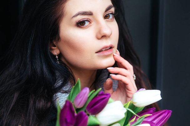 Close-up portrait of young beautiful brunette woman with tulips - Фото, зображення