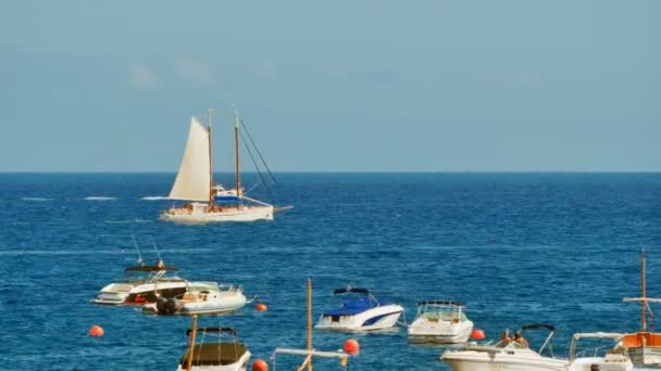 Sailboat Sailing in Crystal Clear Waters. Sailing and anchored boats in the Mediterranean sea. Wooden traditional boats and modern ships. Sunny day sailing the ocean with crystal waters. - Footage, Video