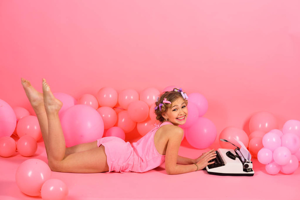 Child in underwear with typewriter on pink background. - Foto, Imagem