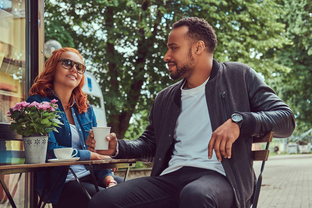 Пара, пьющая кофе, сидящая возле кофейни. На открытом воздухе на свидание
. - Фото, изображение