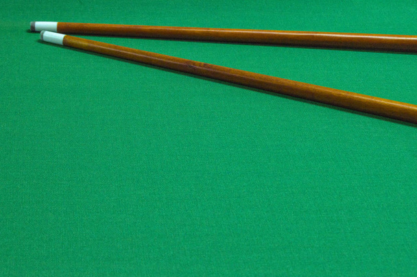 бильярдные кии / два бильярдных кия на зеленом фоне бильярдного стола
 - Фото, изображение
