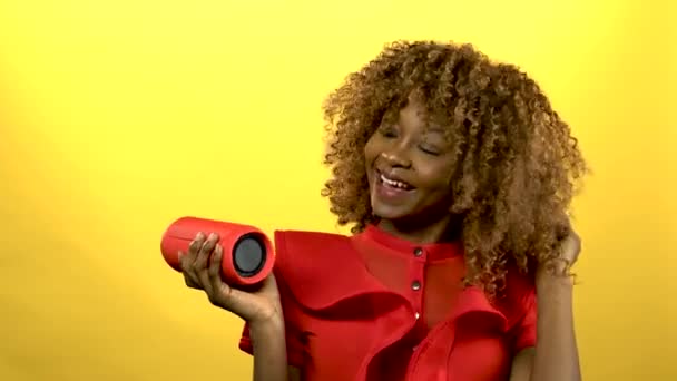 African woman holding a player and dancing .Yellow background - Imágenes, Vídeo