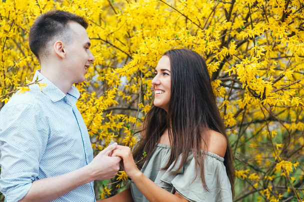 Young happy couple in love outdoors. Man and woman on a walk in a spring blooming park - Foto, Imagen