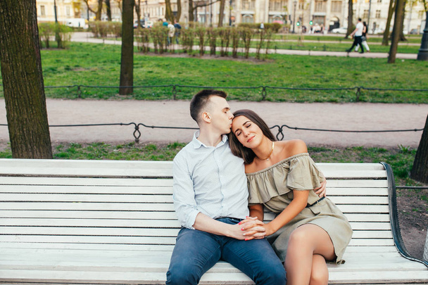 Happy young couple in love sitting on a park bench and hugging - Φωτογραφία, εικόνα