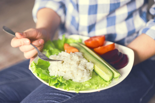 A girl holds a plate with rice and vegetables - Foto, imagen
