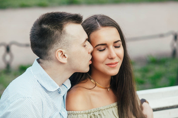 Happy young couple in love sitting on a park bench and hugging - Фото, зображення
