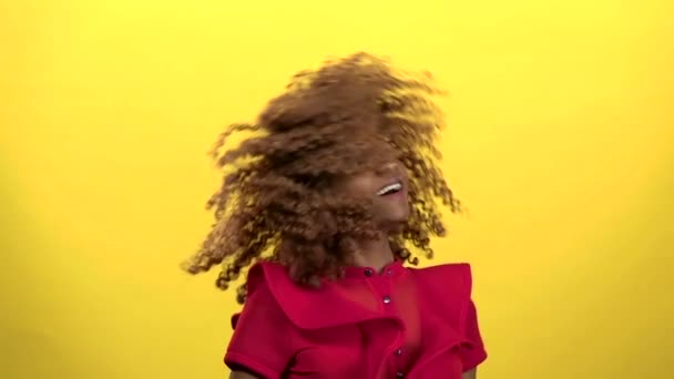 African american makes flies hair. Yellow background. Slow motion - Metraje, vídeo