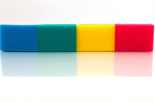 Esponjas coloreadas de goma de espuma, colocadas en el borde en una fila en línea recta
. - Foto, imagen