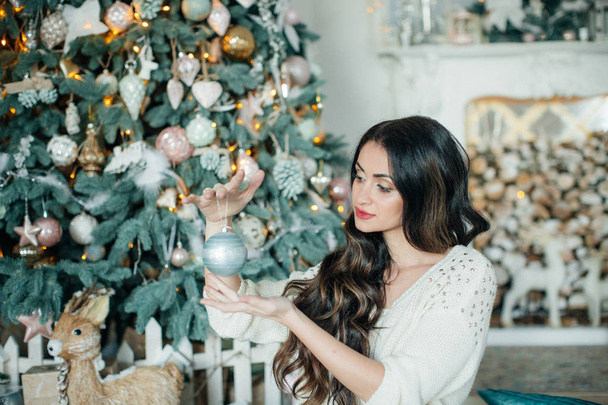 Beautiful woman in dress near Christmas tree posing at home - 写真・画像