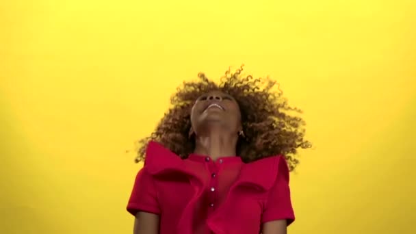 Girl jumps up and has fun. Yellow background. Slow motion - Metraje, vídeo