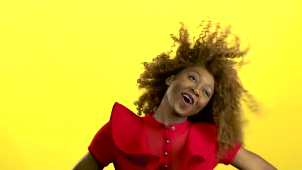 African american girl jumping and having fun with music. Yellow background. Slow motion - Materiał filmowy, wideo