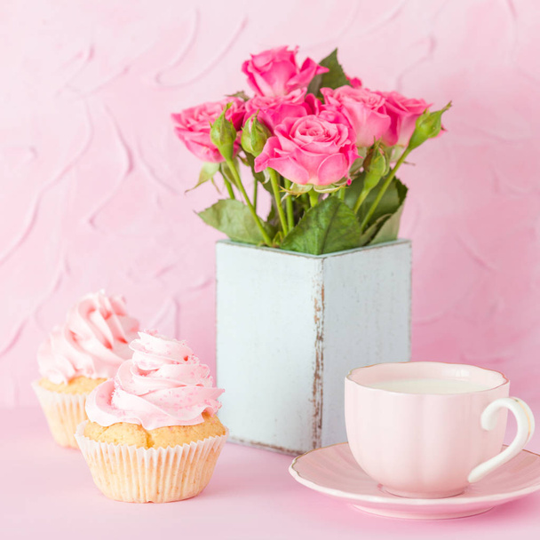 Розовый пастельный баннер с украшенными кексами, чашка кофе с молоком и букет розовых роз
. - Фото, изображение