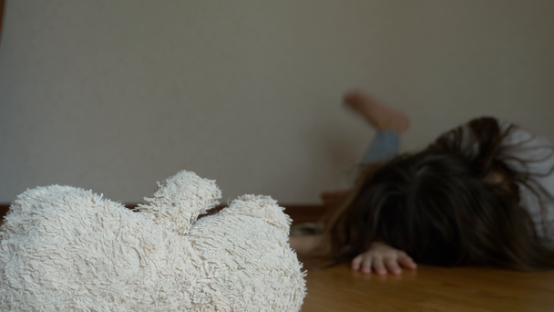 un niño desesperado en depresión se sienta en la pared de su habitación, intenta suicidarse. junto a ella hay un juguete suave abandonado. 4k, cámara lenta
. - Metraje, vídeo