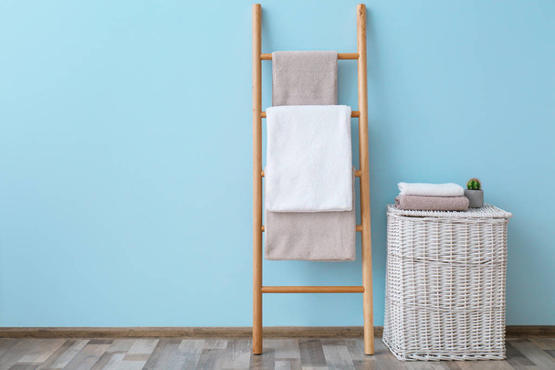 Schone handdoeken op de houder en rieten mand in de badkamer - Foto, afbeelding