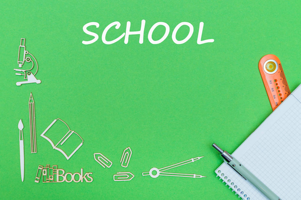 κείμενο σχολείο, σχολικών ειδών ξύλινες μινιατούρες, σημειωματάριο με χάρακα, στυλό πάνω σε πράσινο ταμπλό - Φωτογραφία, εικόνα