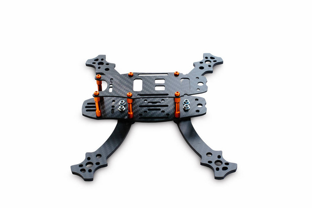 The beginning of the racing drone assembly. A robust frame of an unmanned aerial vehicle made of carbon fiber. Frame of carbon fiber quadrocopter isolated on white background - Photo, Image