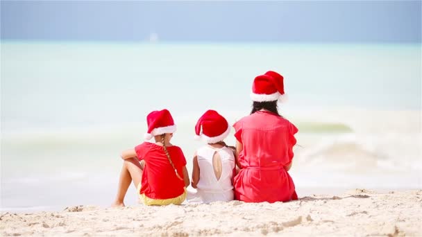 Boldog szép család piros Santa kalap, egy trópusi tengerparton ünnepli a karácsonyt. Anya és a gyerekek élvezik a karácsonyi ünnepek - Felvétel, videó