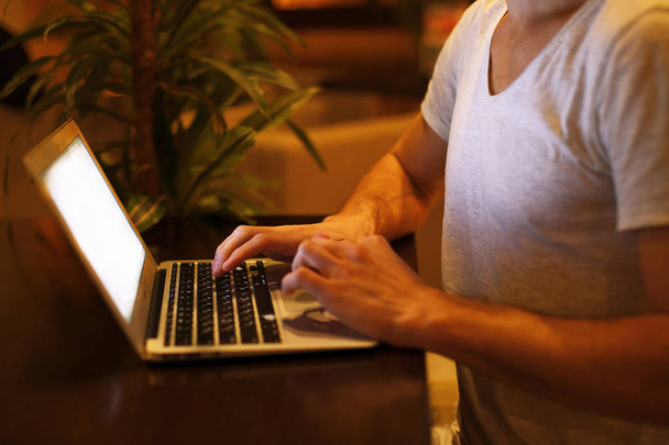 Молодой красивый мужчина сидит в кафе с ноутбуком на закате
 - Фото, изображение